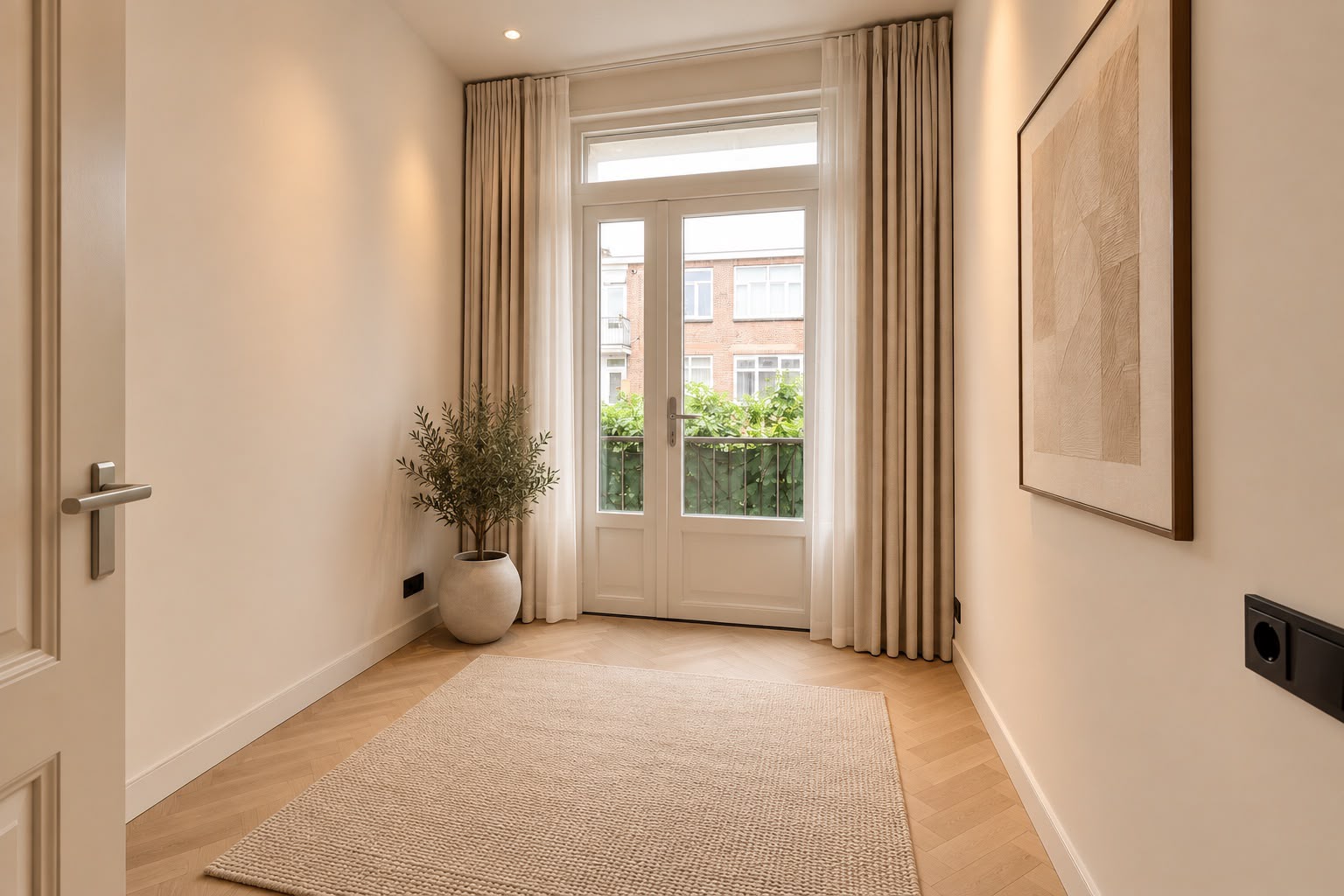 Ingerichte kamer na renovatie met lichte wanden, houten vloer en openslaande deuren.