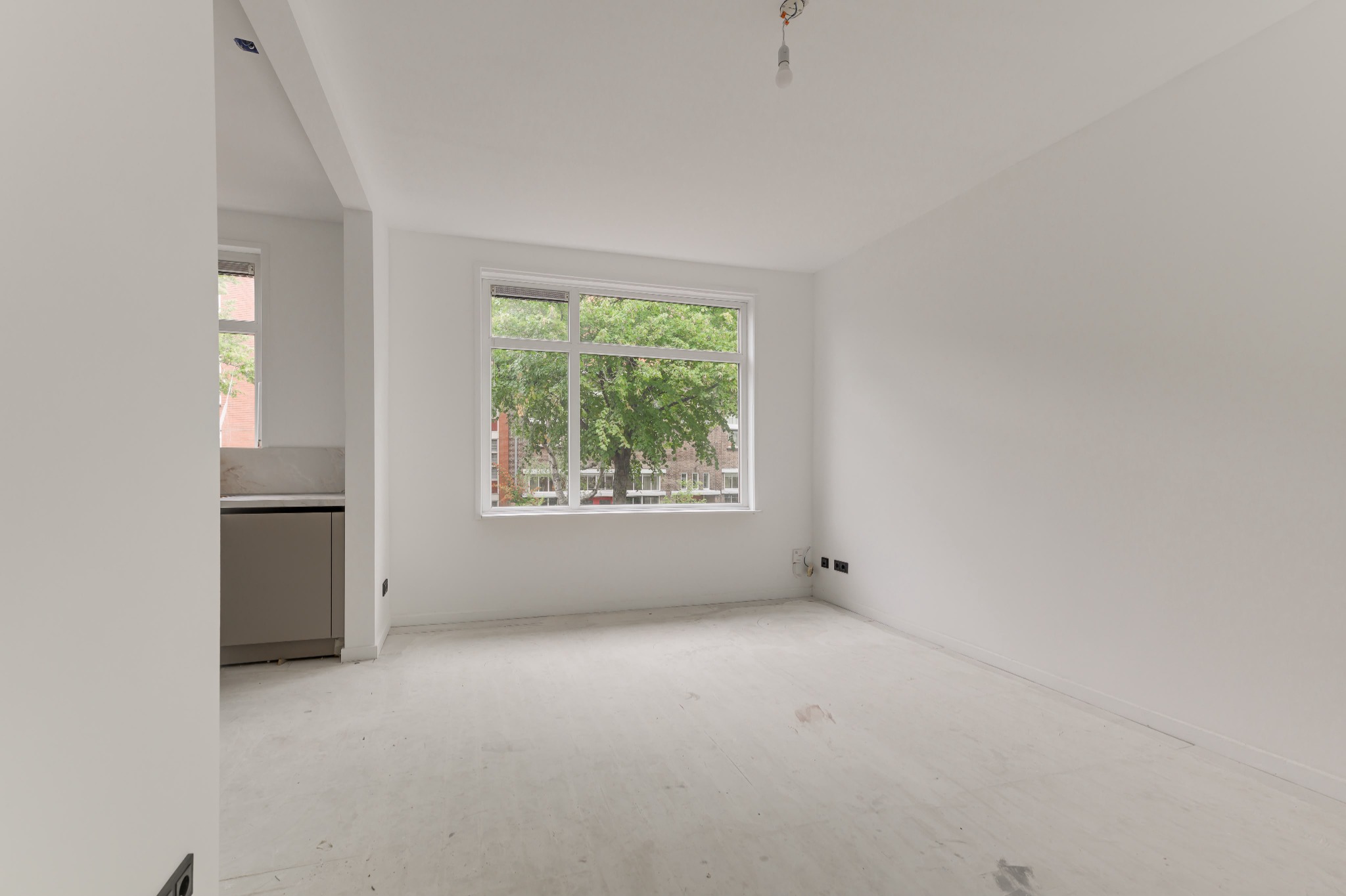 Lege, afgewerkte woonkamer in Den Haag met lichte wanden en plafond, klaar om ingericht te worden.